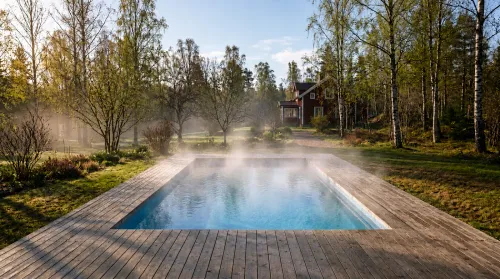 Öppen pool utan överdrag en kylig vårmorgon – vattenångan är värme som lämnar poolen