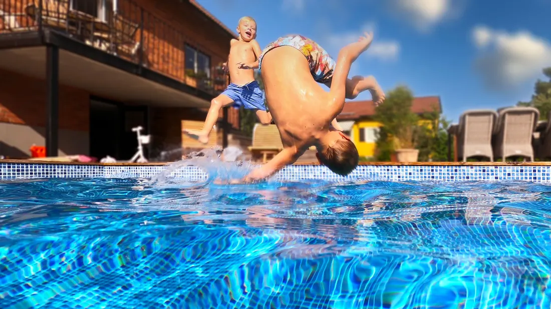 Barn som hoppar i poolen