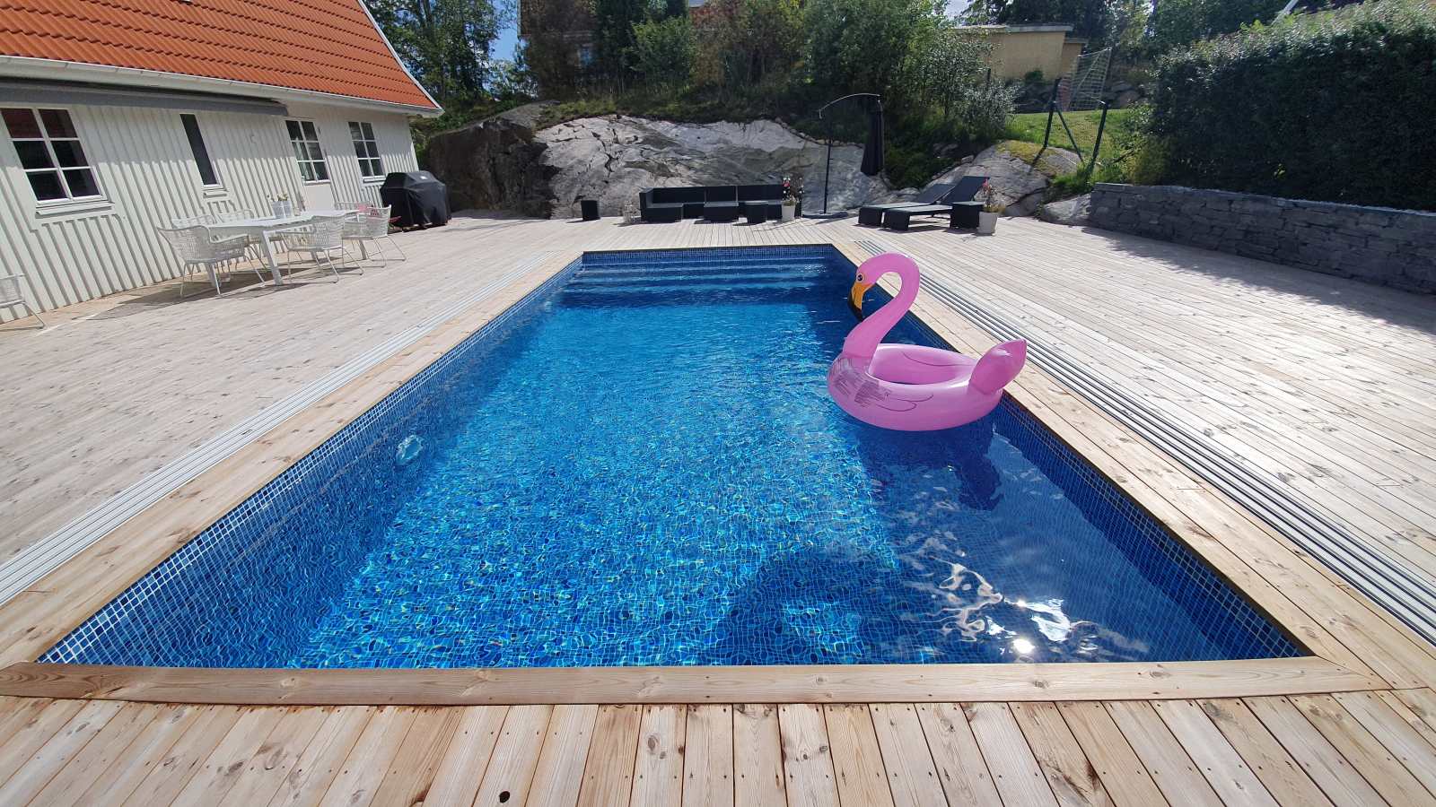 Pool med trädäck framför berget i Huddinge
