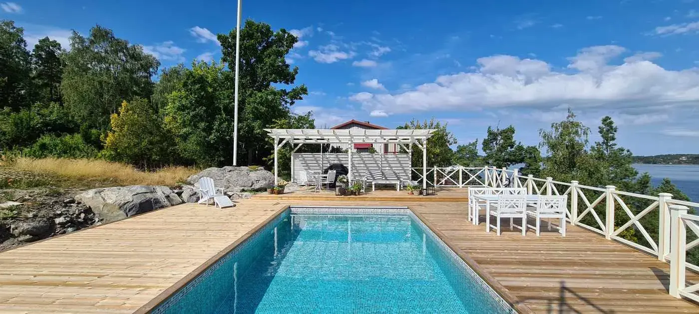 Pool med vit pergola och havsutsikt i Tyresö